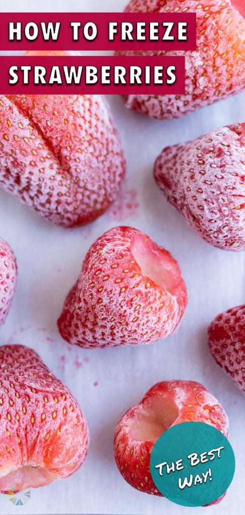 A baking sheet is filled with frozen strawberries.