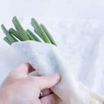 A wet paper towel is wrapped around the green onions.