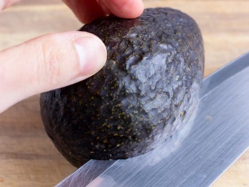Cut an avocado in half with a sharp knife