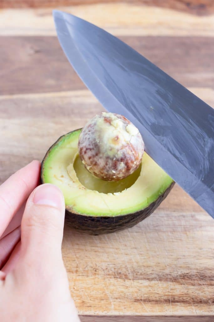 Use the edge of a knife to carefully remove the pit of an avocado.