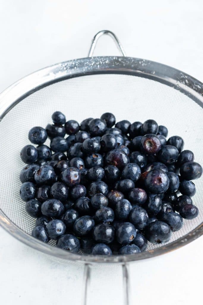 Fresh blueberries are prepared and washed before laying flat.