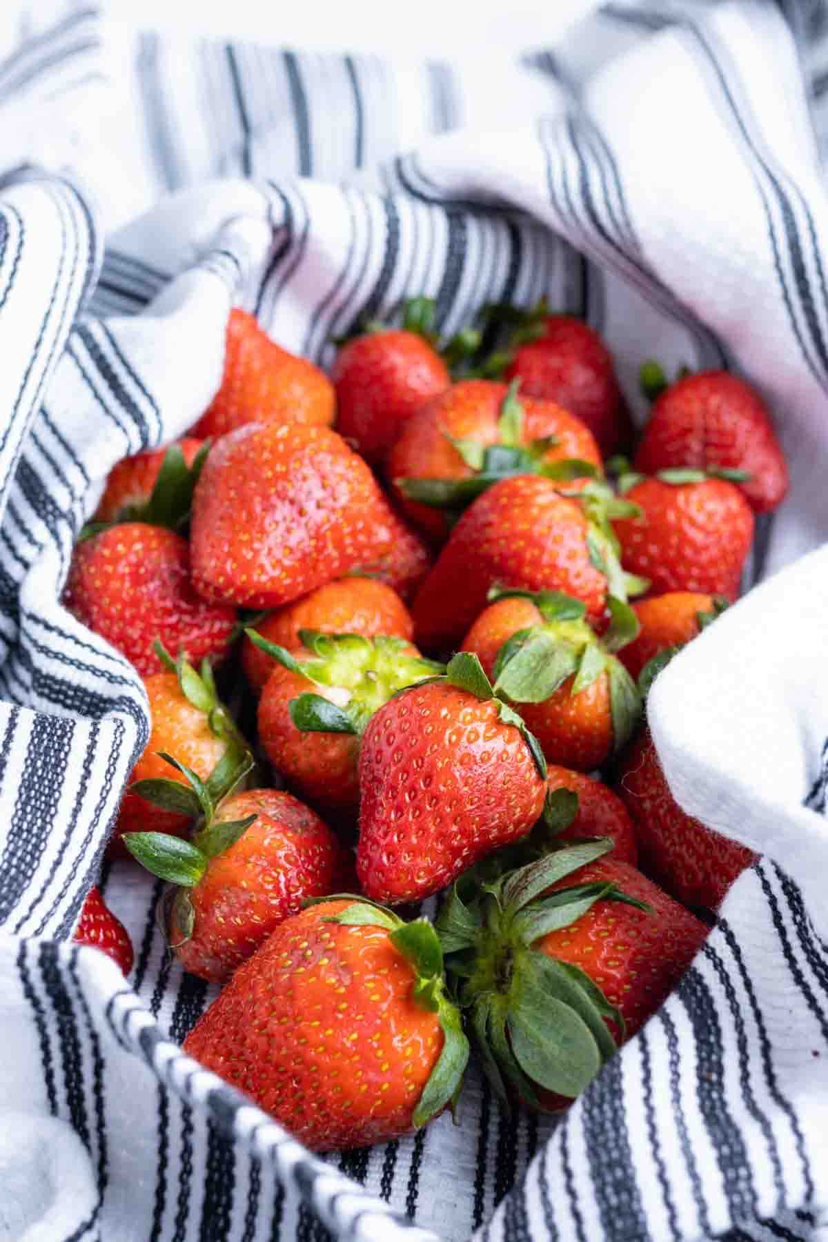 Strawberries are shown in a towel after washing them.
