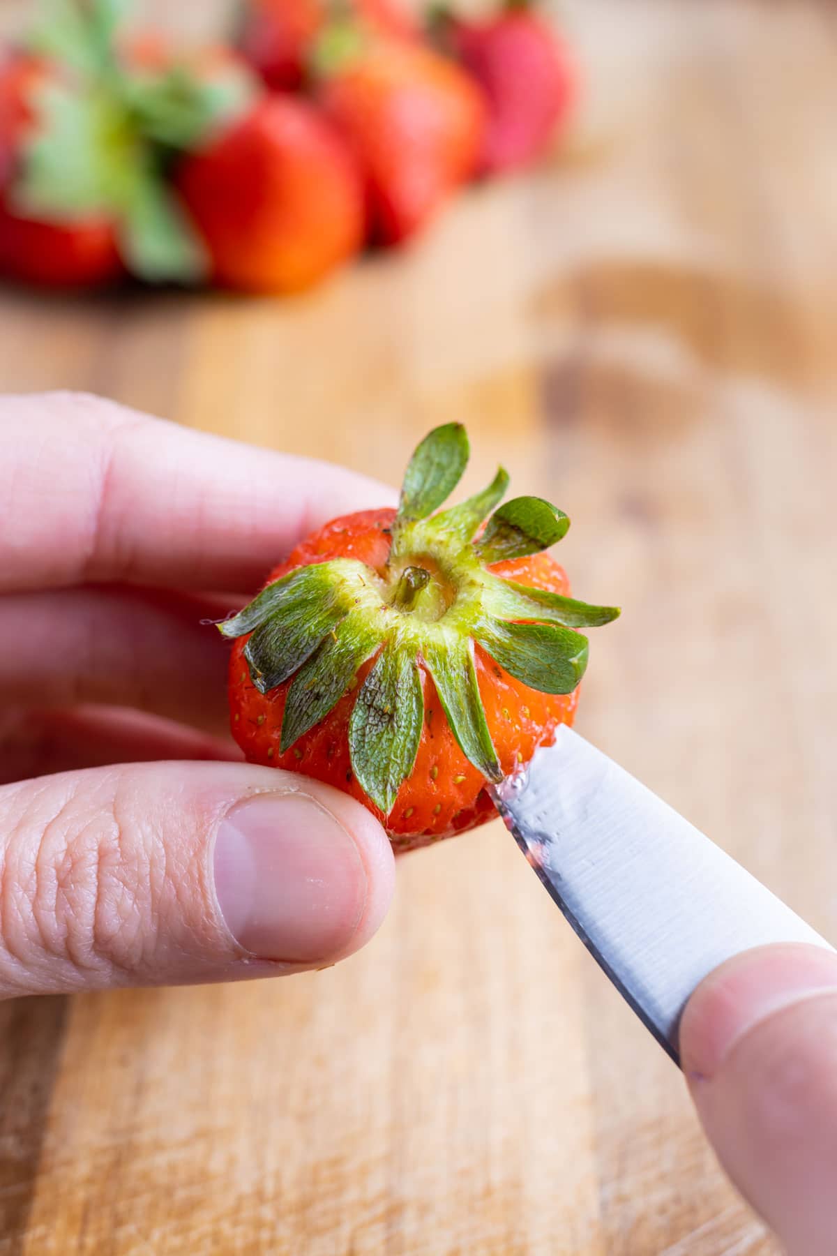 The stem is removed from the strawberries with a knife.