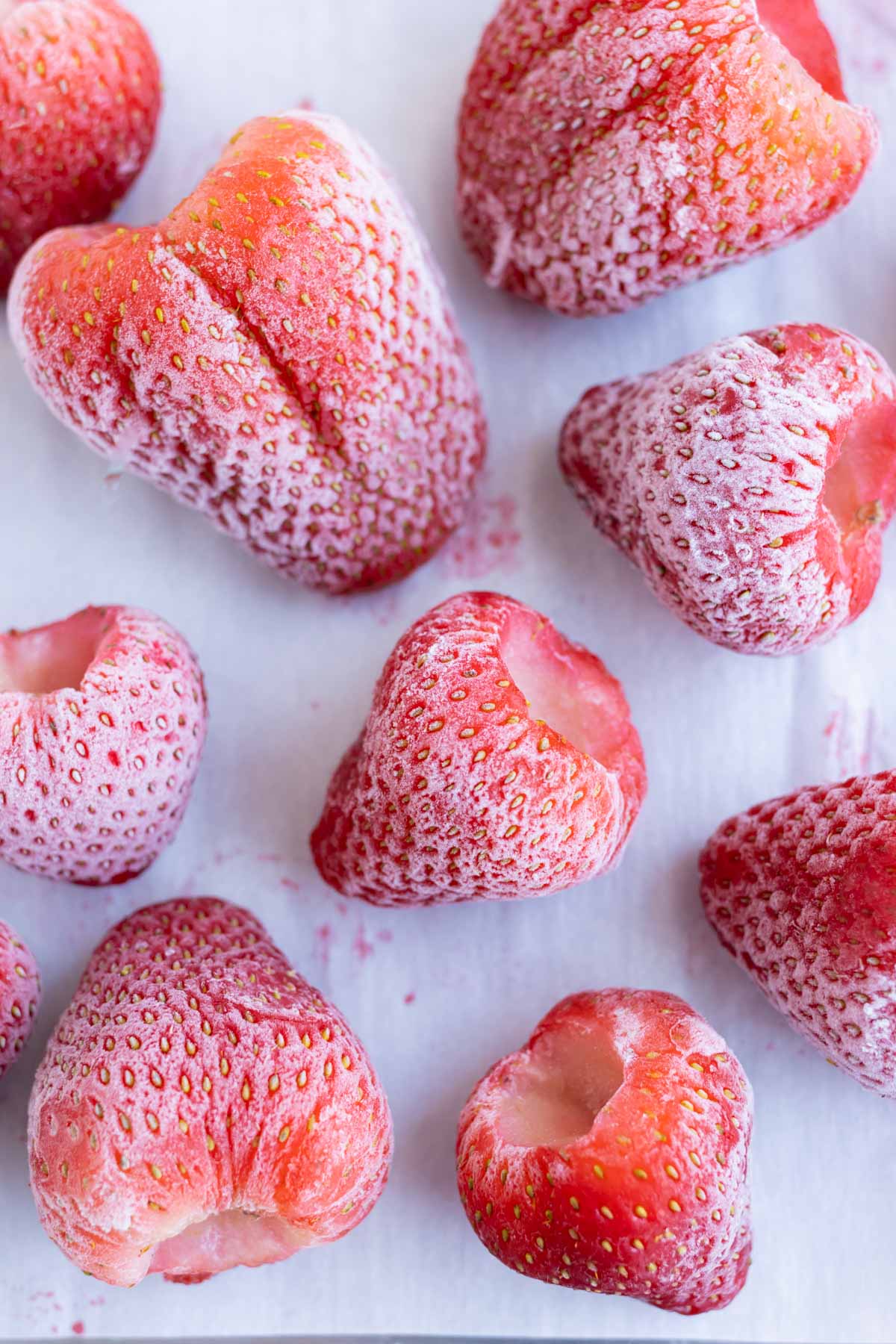 Frozen strawberries are shown on a baking sheet.
