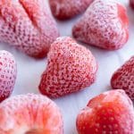 Strawberries are shown on a baking sheet after being frozen.