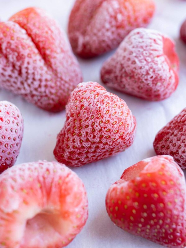 Strawberries are shown on a baking sheet after being frozen.