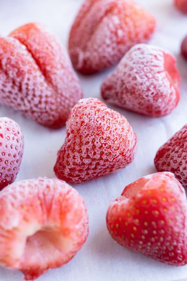 Strawberries are shown on a baking sheet after being frozen.