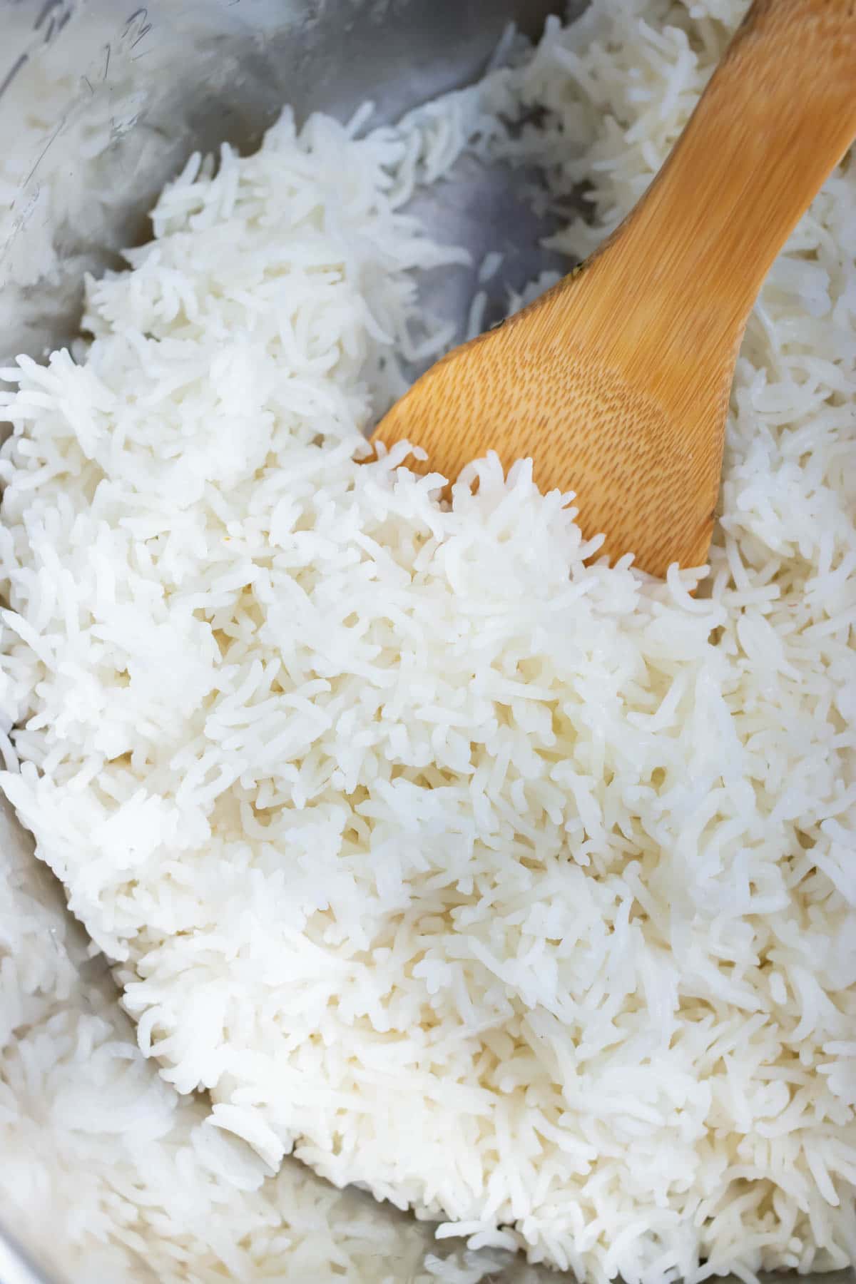 Cooked basmati rice in an Instant Pot with a wooden spoon stuck in it.