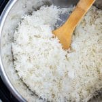 Cooked basmati rice in an Instant Pot with a wooden spoon stuck in it.