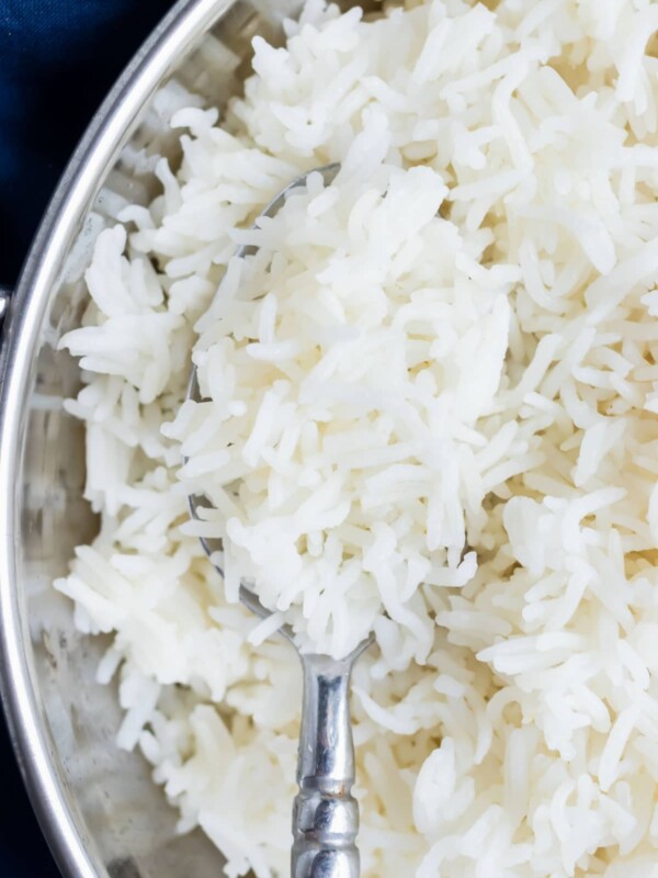A closeup of cooked rice being spooned out of a metal serving dish.