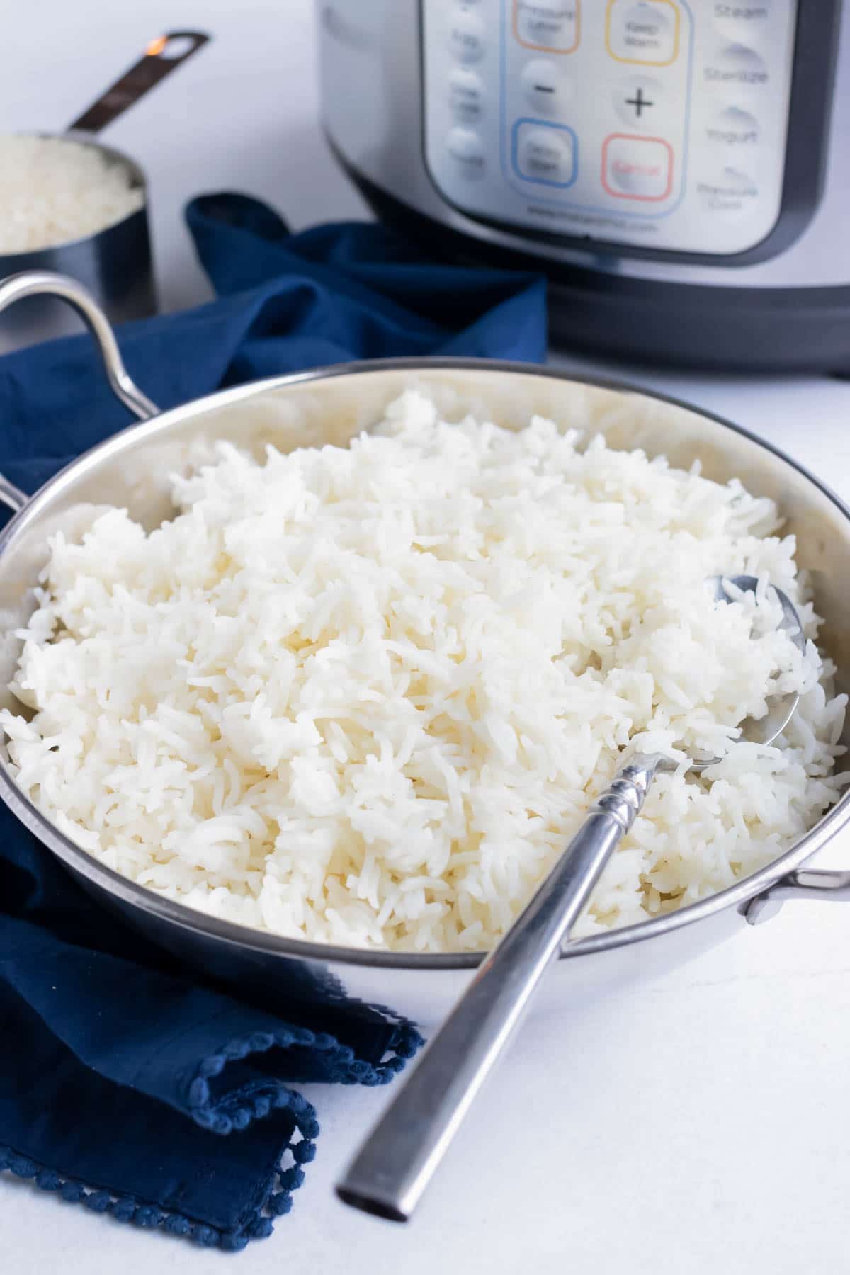 An Indian silver metal serving bowl full of basmati rice with an Instant Pot.