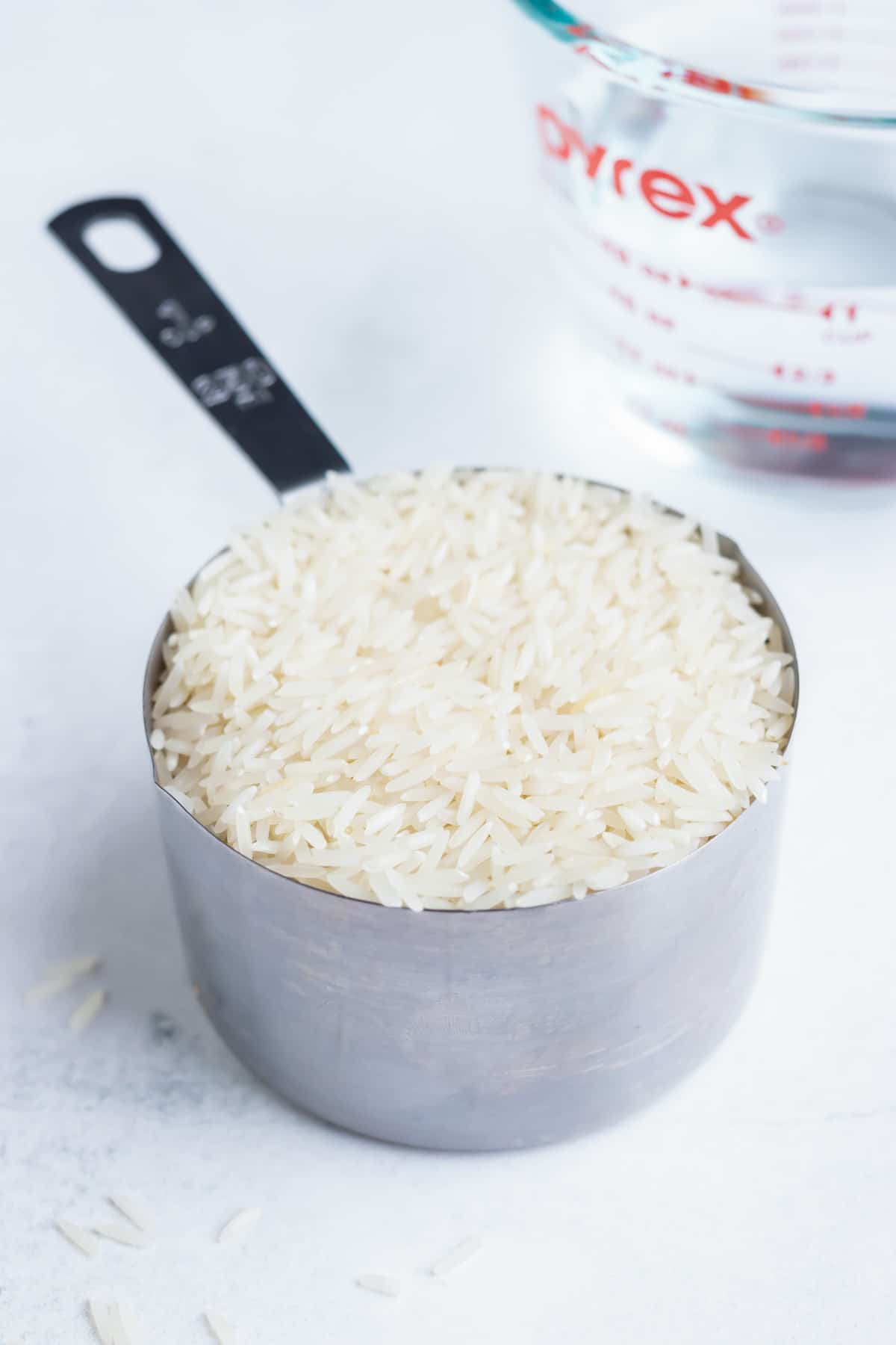Dried rice filling a metal measuring cup.