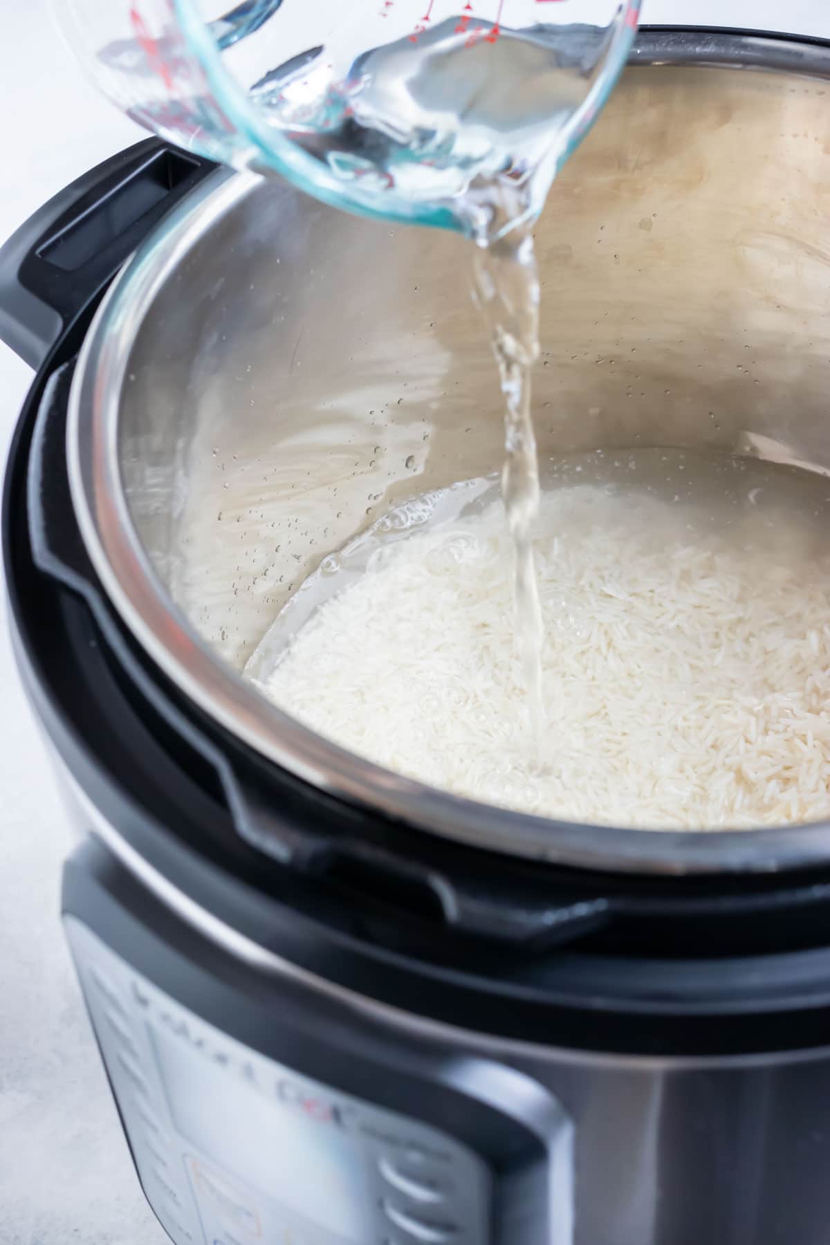Rice and water being added to an Instant Pot for cooking.