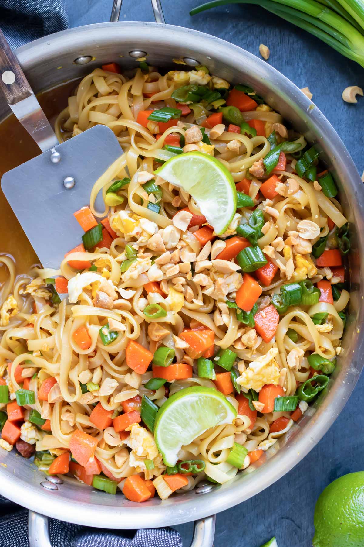 A large skillet full of a vegetarian Pad Thai recipe with limes.