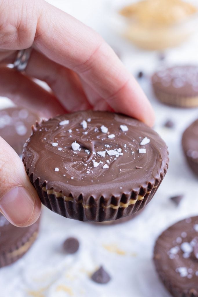 A hand is shown holding a peanut butter cup.