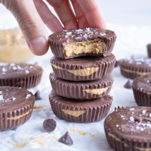 Peanut butter cups are shown as a hand reaches to eat one.