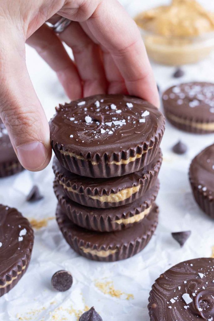 Peanut butter cups are reached for by a hand.