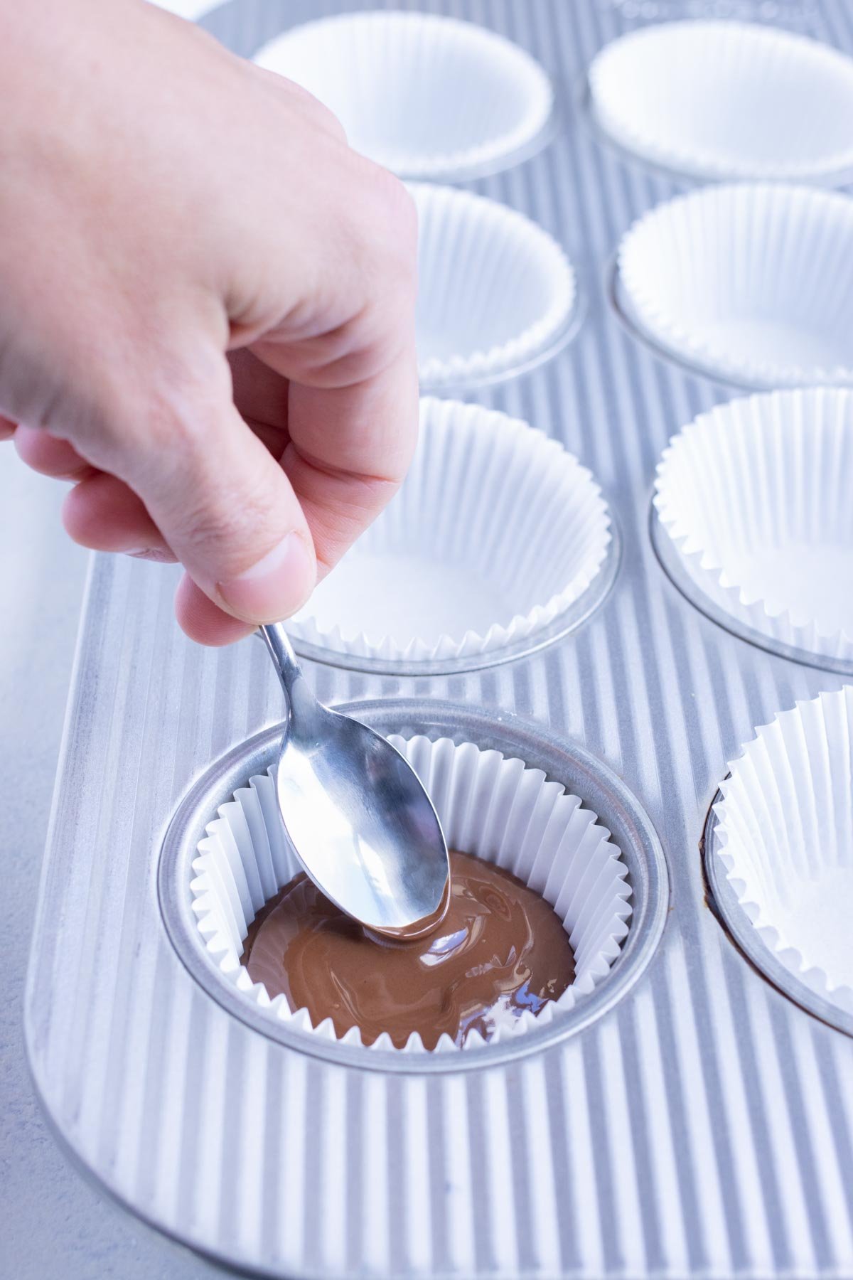 Chocolate is spooned on top of the peanut butter cup.