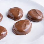 Chocolate peanut butter eggs are laid on wax paper to set.
