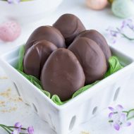 Six chocolate peanut butter eggs are shown in a ceramic basket.