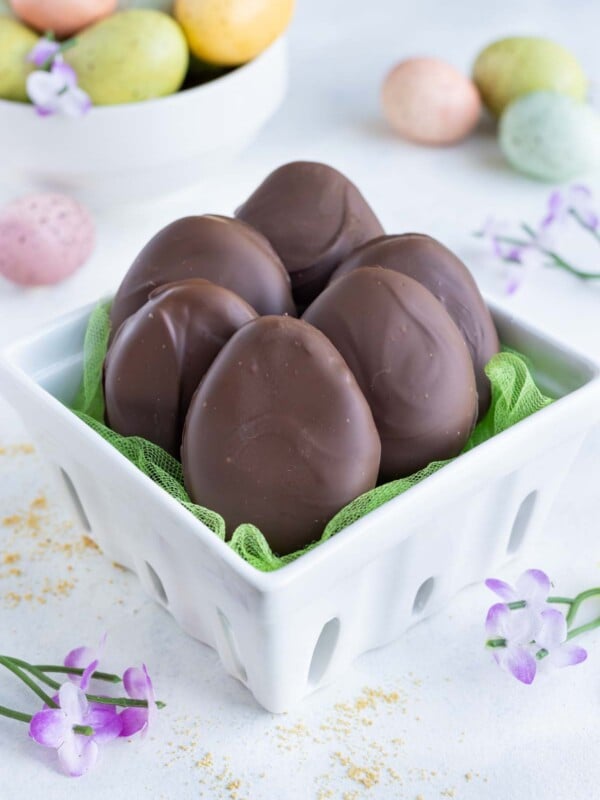 Six chocolate peanut butter eggs are shown in a ceramic basket.