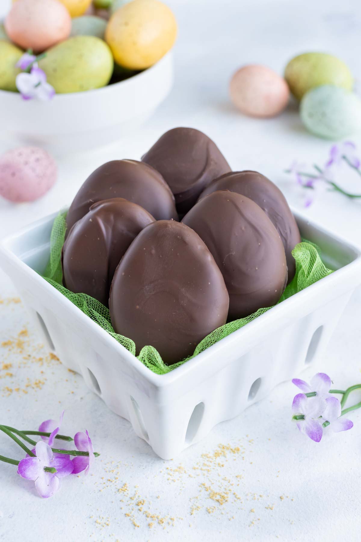 Six chocolate peanut butter eggs are shown in a ceramic basket.