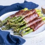 A plate of prosciutto-wrapped asparagus is served on a plate for an easy side dish.