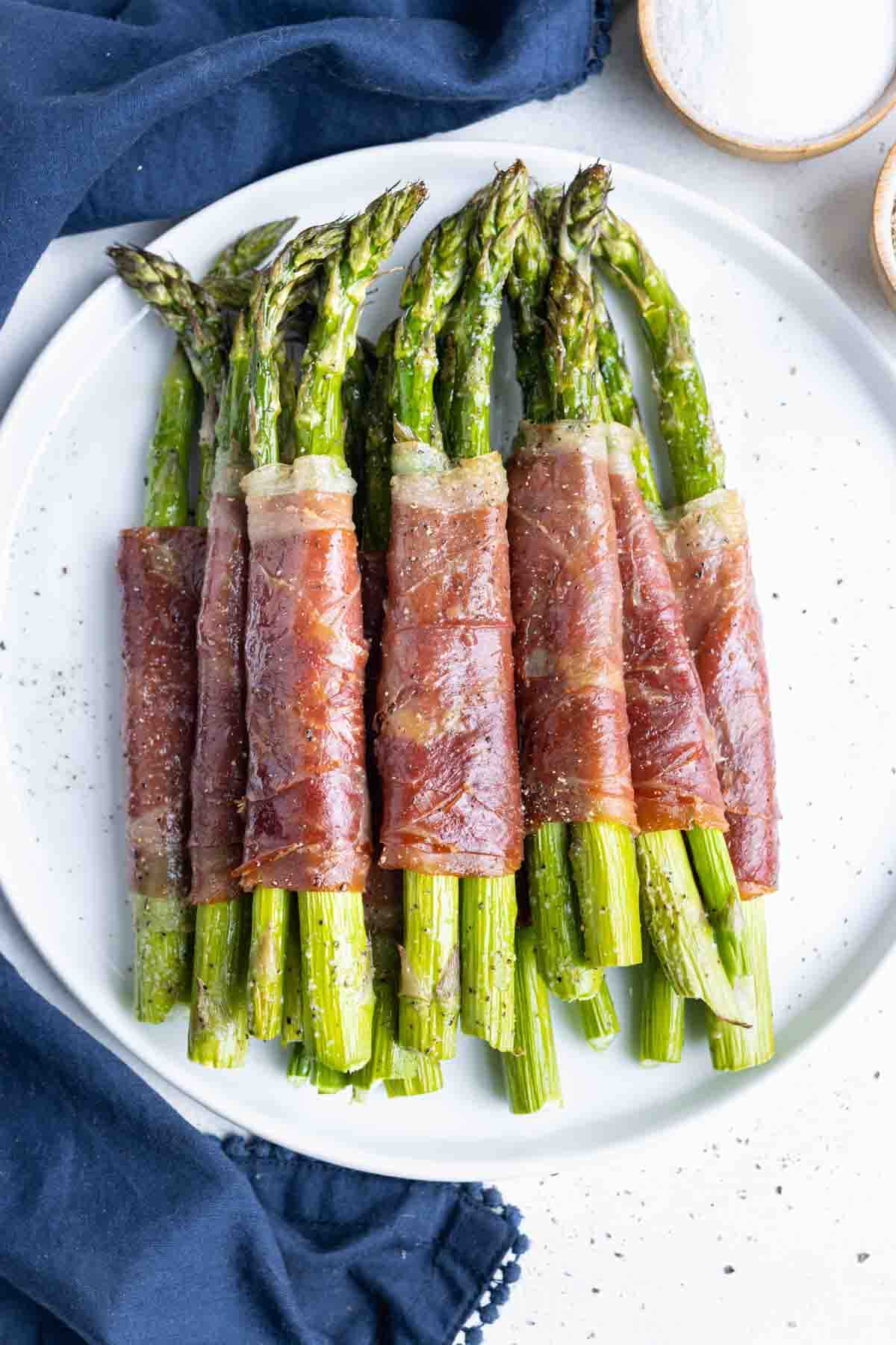 Asparagus baked in the oven and wrapped in prosciutto is served on the counter.