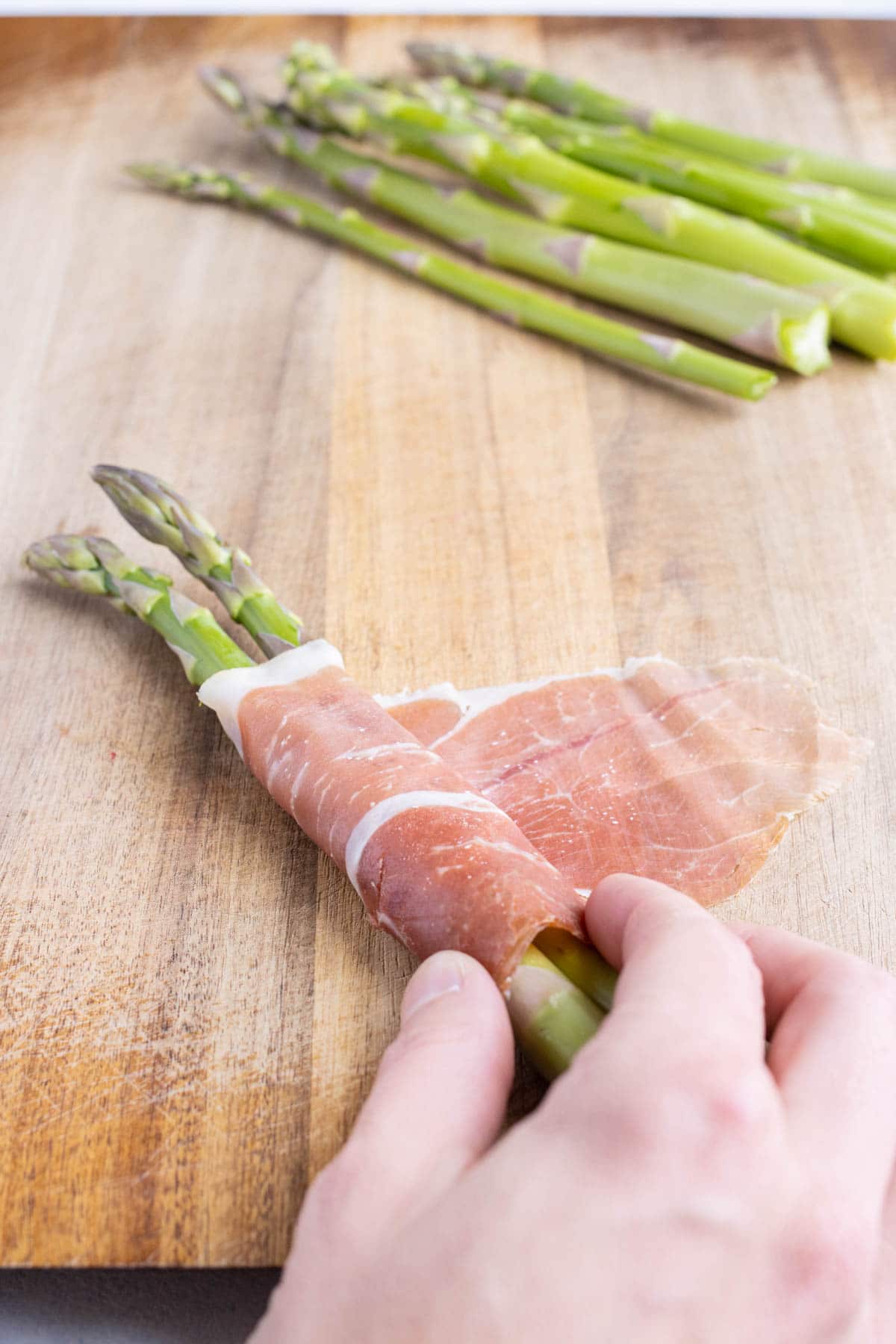 Thin prosciutto is wrapped around asparagus bundles.