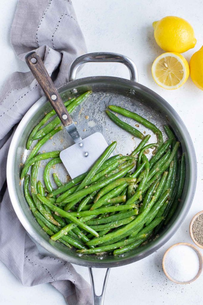 Easy green beans with garlic are cooked on the stove in a skillet.