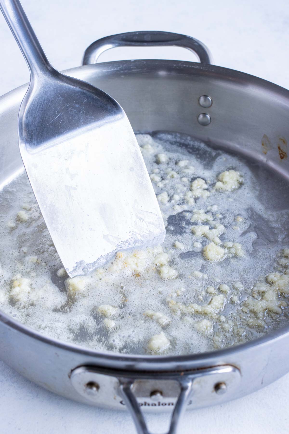 Butter is melted on the stove with minced garlic.