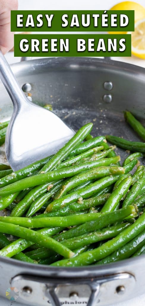 A spatula is used to remove the green beans from the skillet.