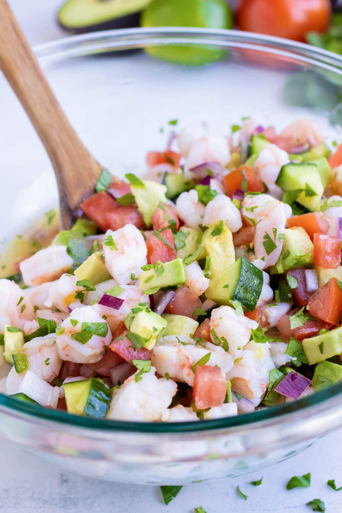 Shrimp ceviche is mixed thoroughly in a large glass bowl before being served.