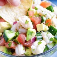 Low-Carb, healthy, and easy Mexican Shrimp Ceviche with a hand dipping a chip into it.
