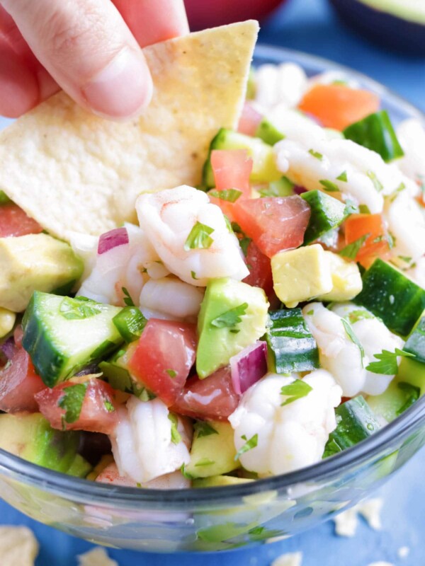 Low-Carb, healthy, and easy Mexican Shrimp Ceviche with a hand dipping a chip into it.