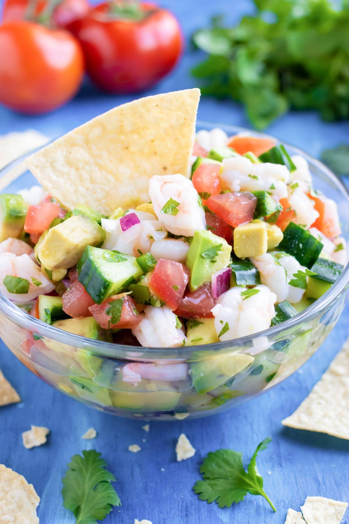 A clear bowl full of an easy shrimp ceviche recipe with a tortilla chip in it.