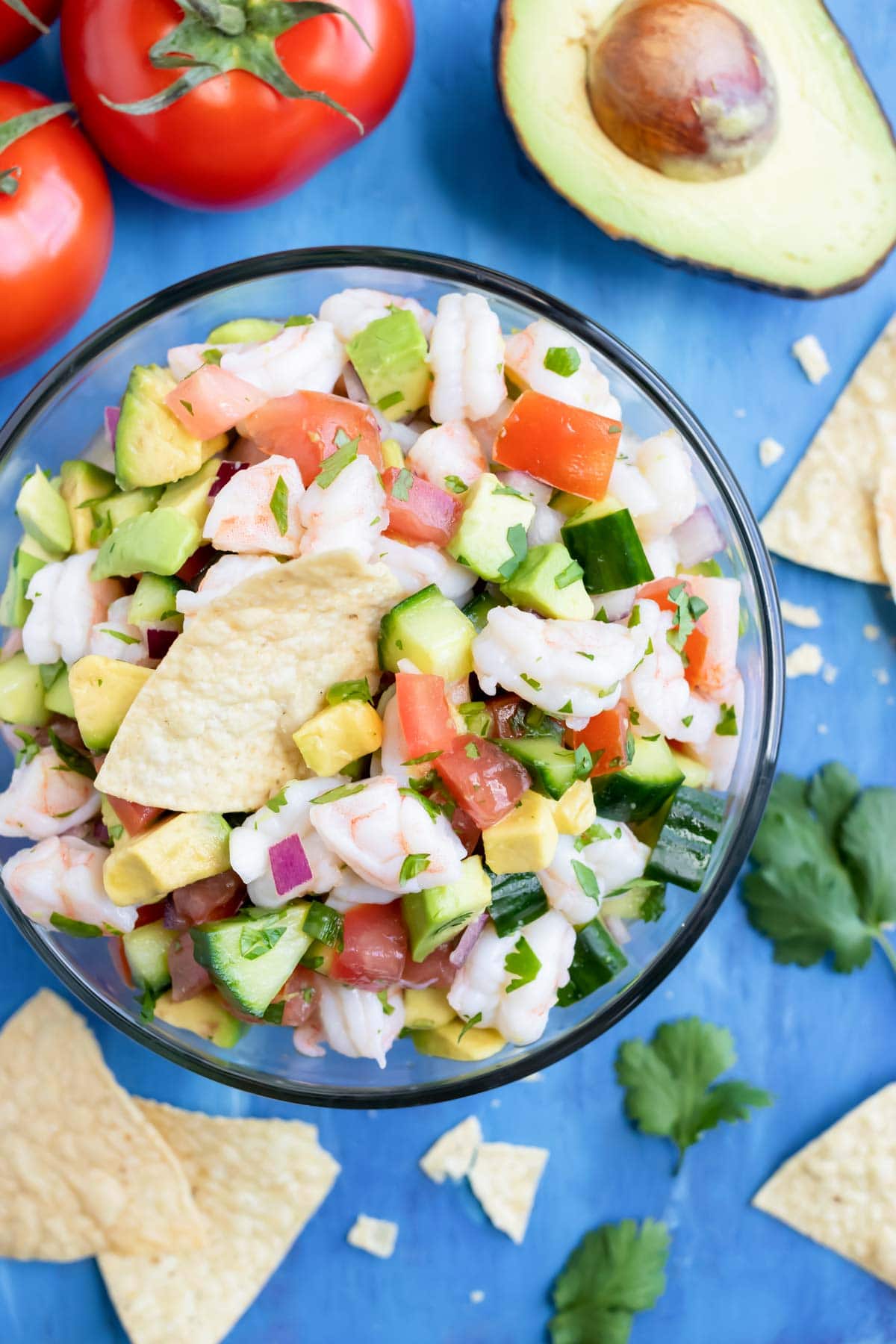 An appetizer bowl full of a shrimp and avocado Mexican dip recipe surrounded by tortilla chips.