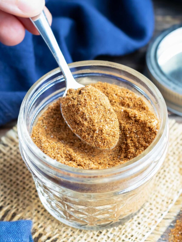 A hand scooping out a teaspoon of DIY taco seasoning to use in a recipe.