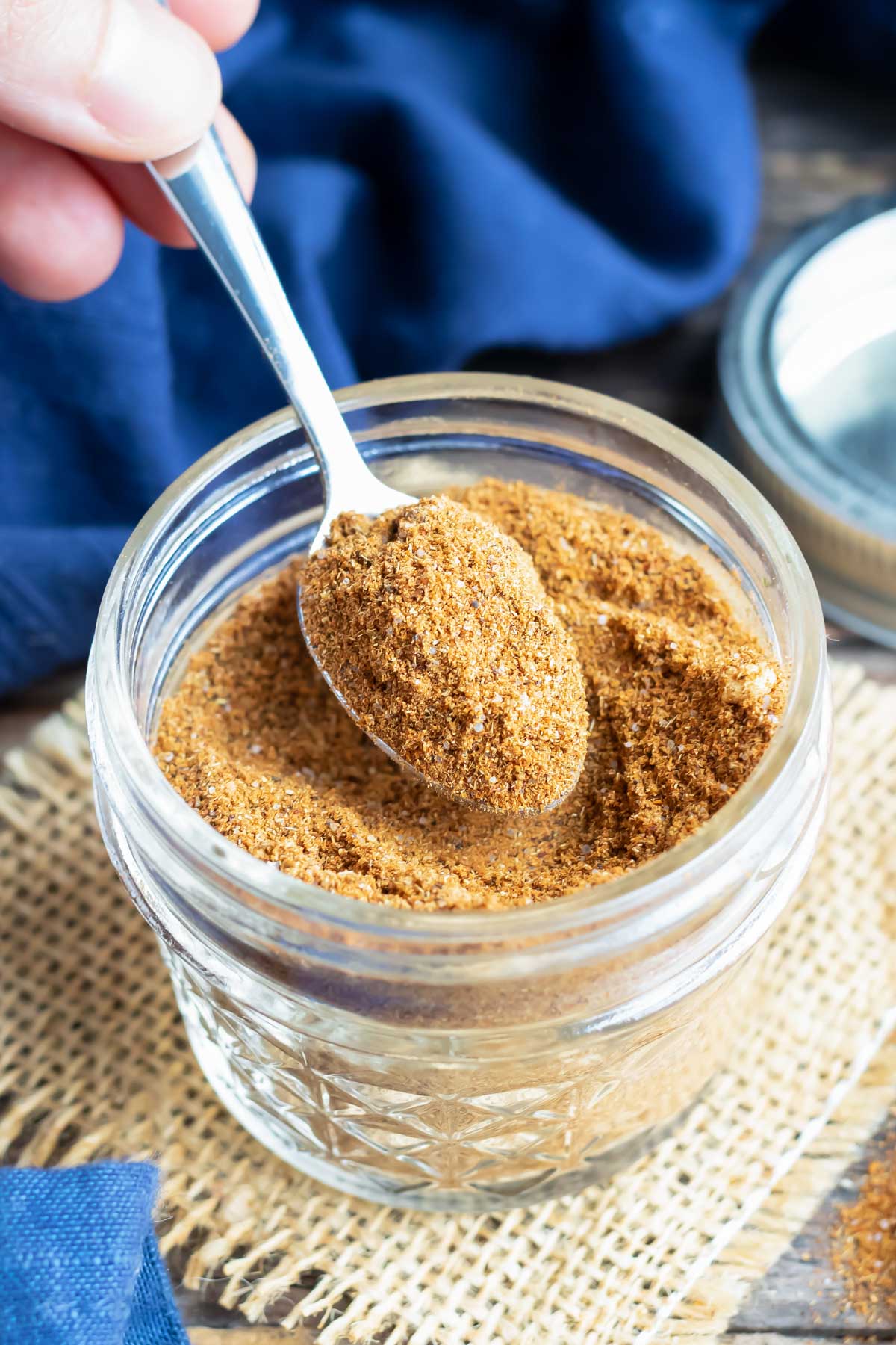 A hand scooping out a teaspoon of DIY taco seasoning to use in a recipe.