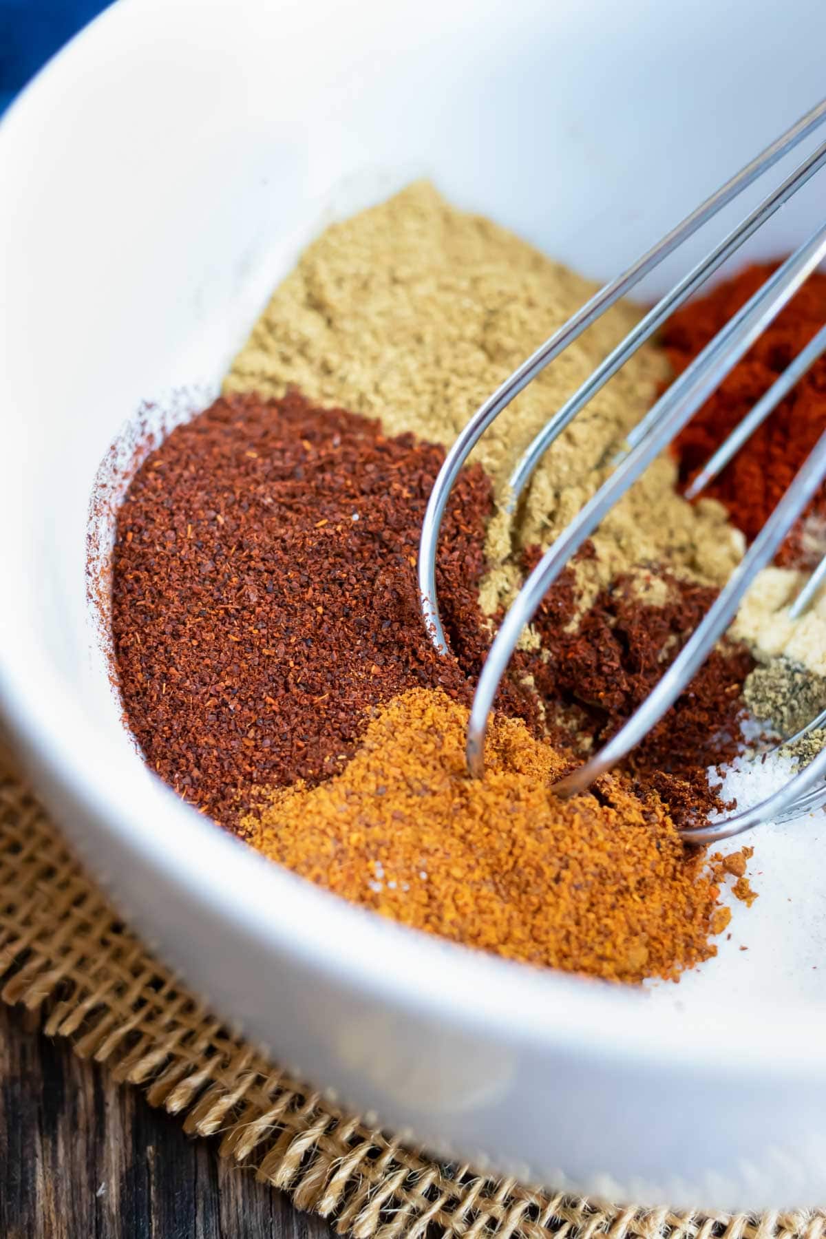 A white bowl full of spices for a DIY taco seasoning mix with a whisk.