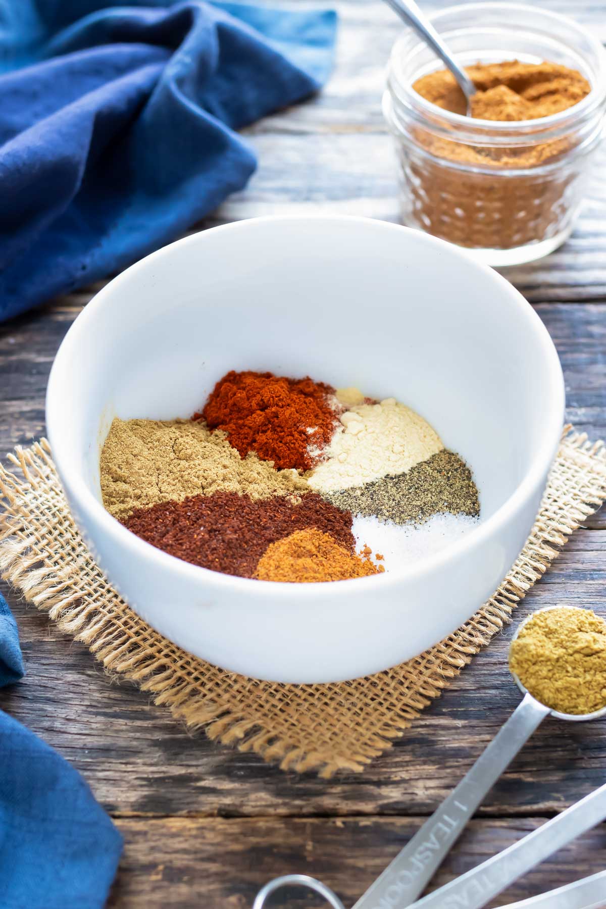 Multiple Mexican spices in a white bowl to make a gluten-free, Paleo, and Whole30 taco seasoning recipe.