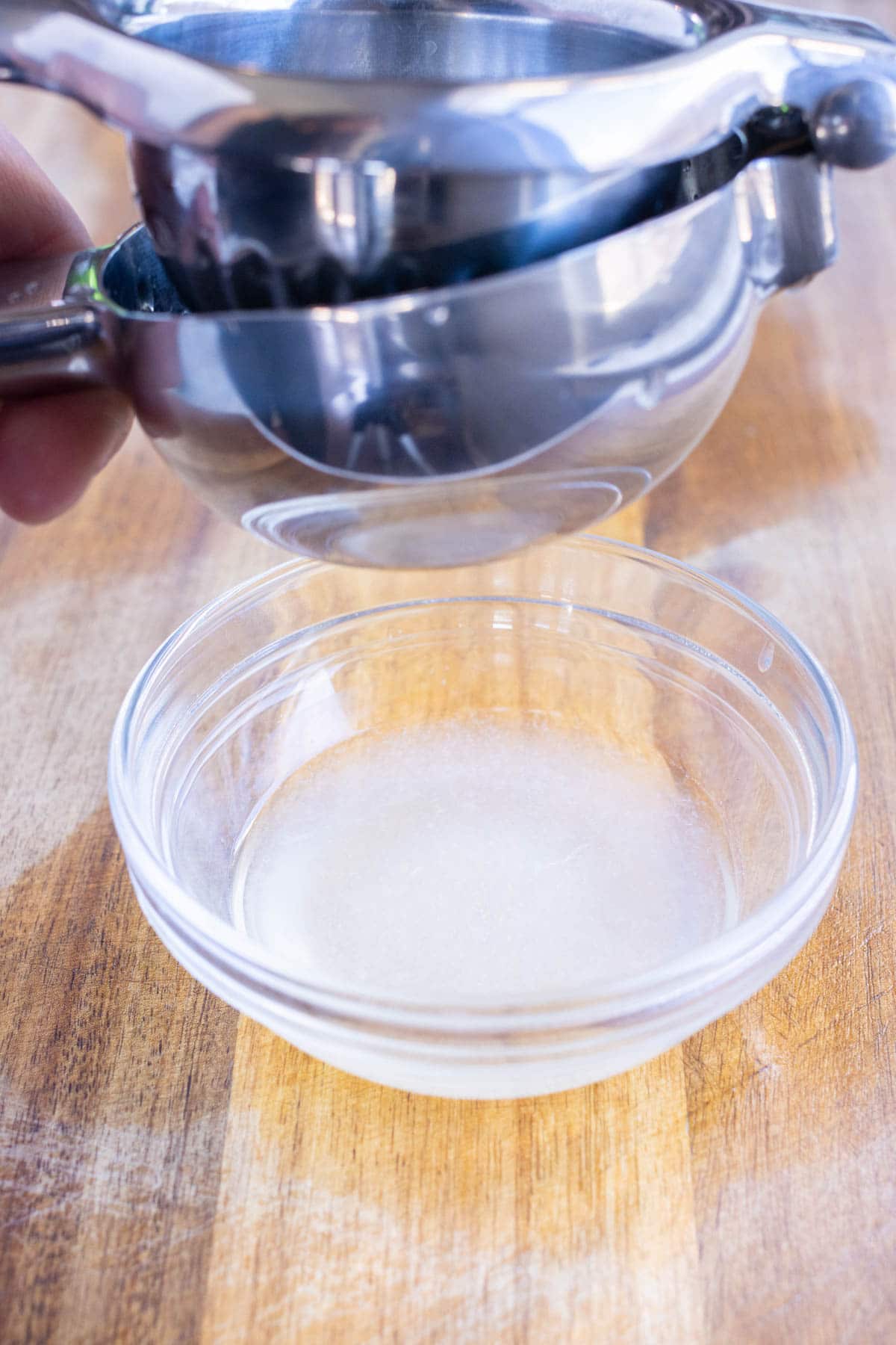 Lime juice is squeezed into a glass cup.