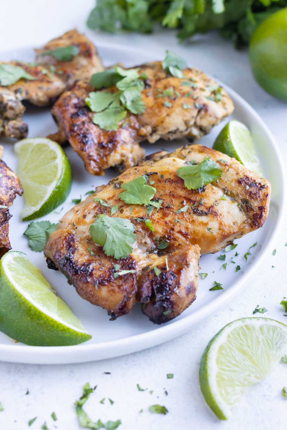 Quick and easy cilantro lime chicken is served on a white plate on the counter.