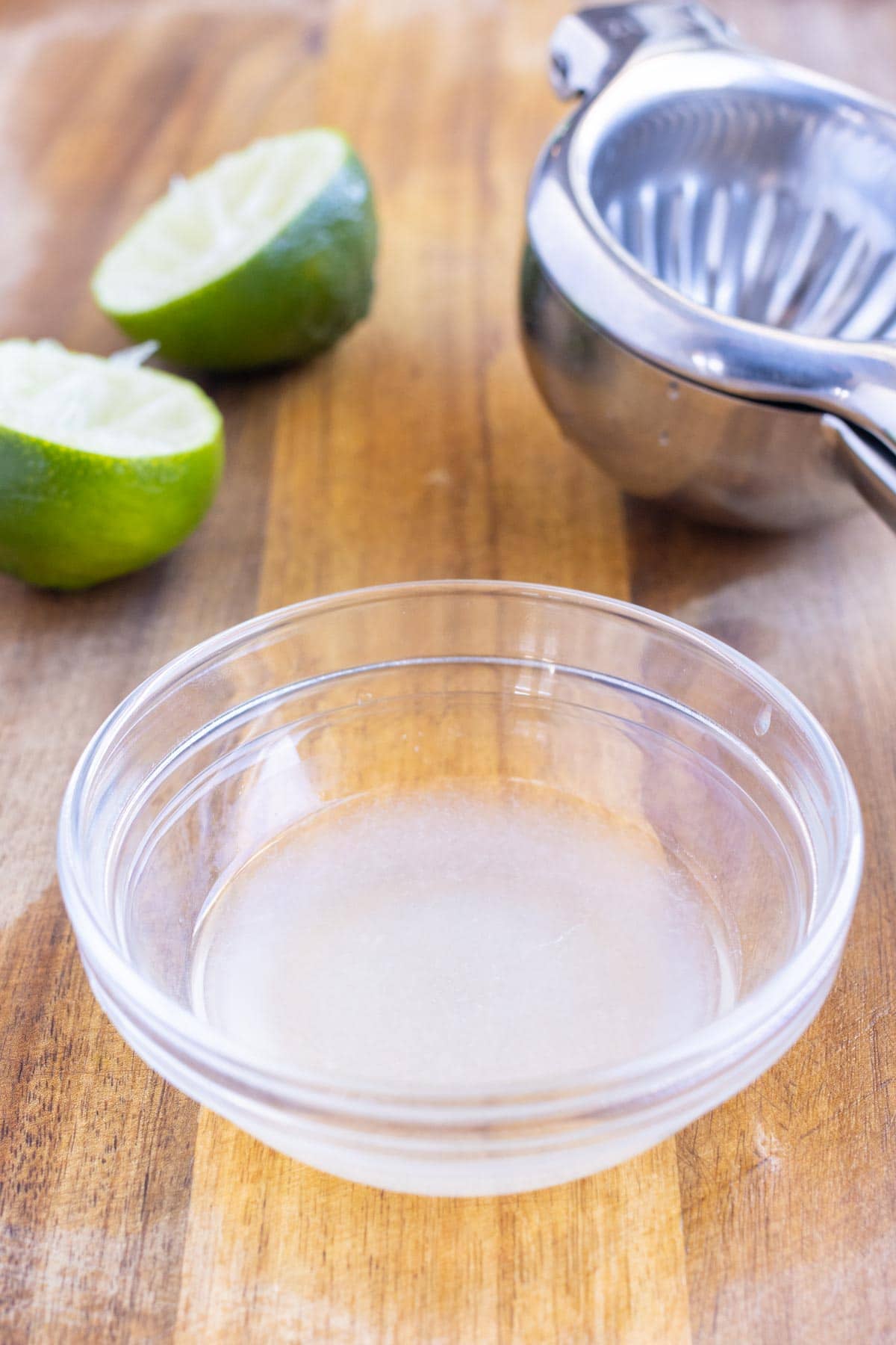 Limes are cut in half and juiced into a bowl.