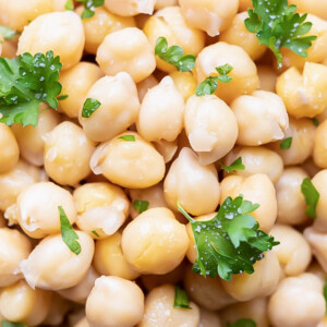A close-up image of cooked garbanzo beans with parsley that shows how to cook chickpeas from scratch.