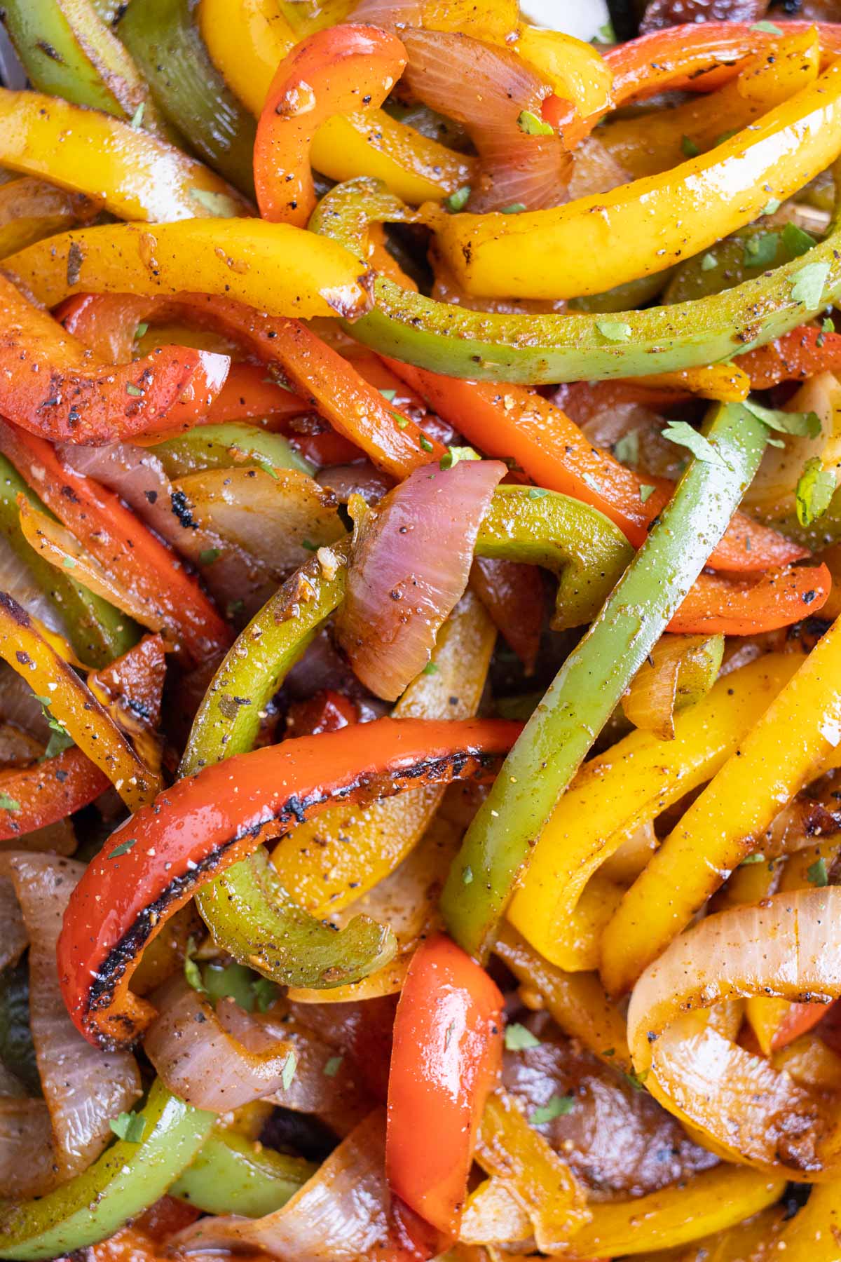Fajita bell peppers and onions are served in a skillet with cilantro.