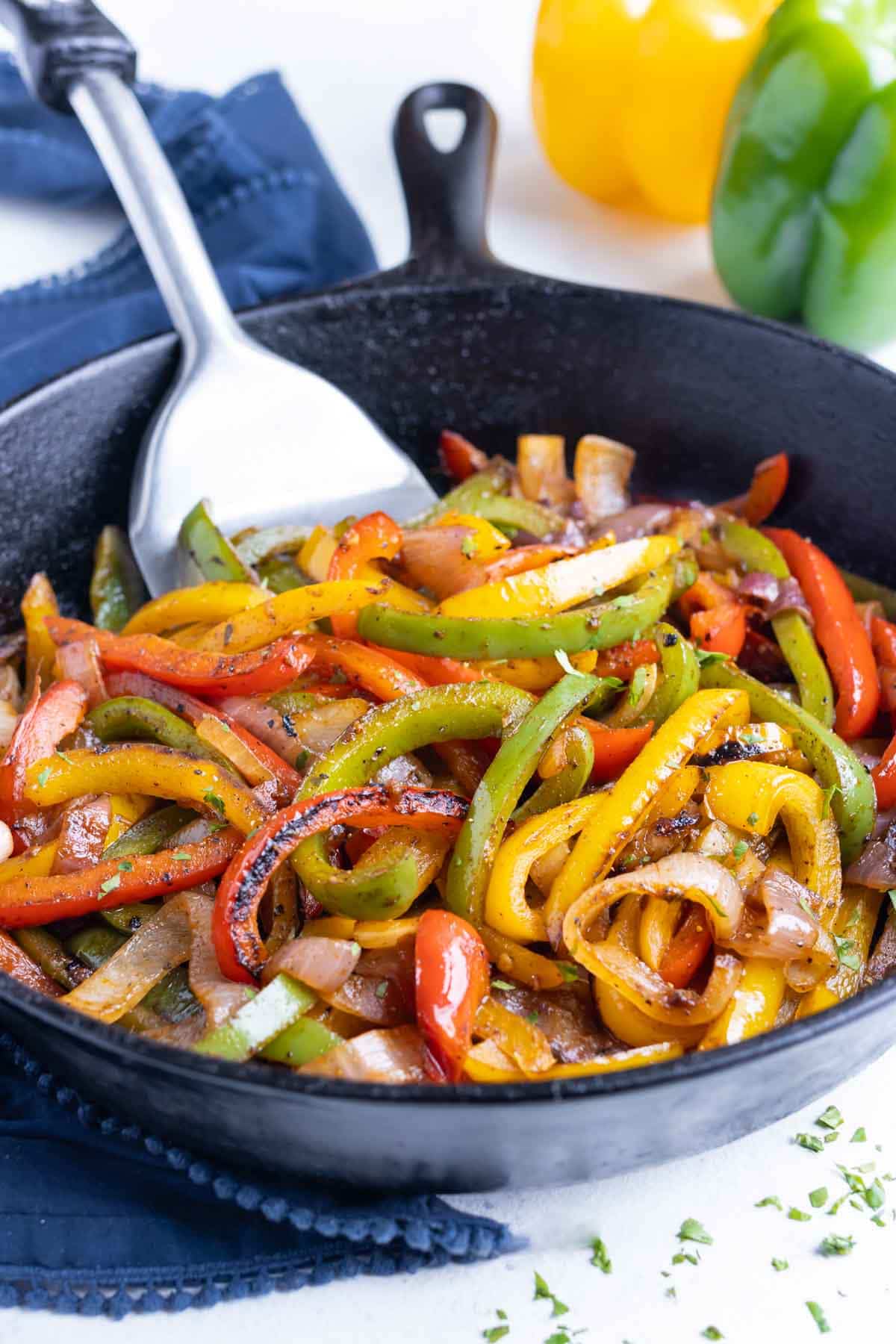 Fajita Veggies RECIPE in a cast iron skillet and a metal spatula.