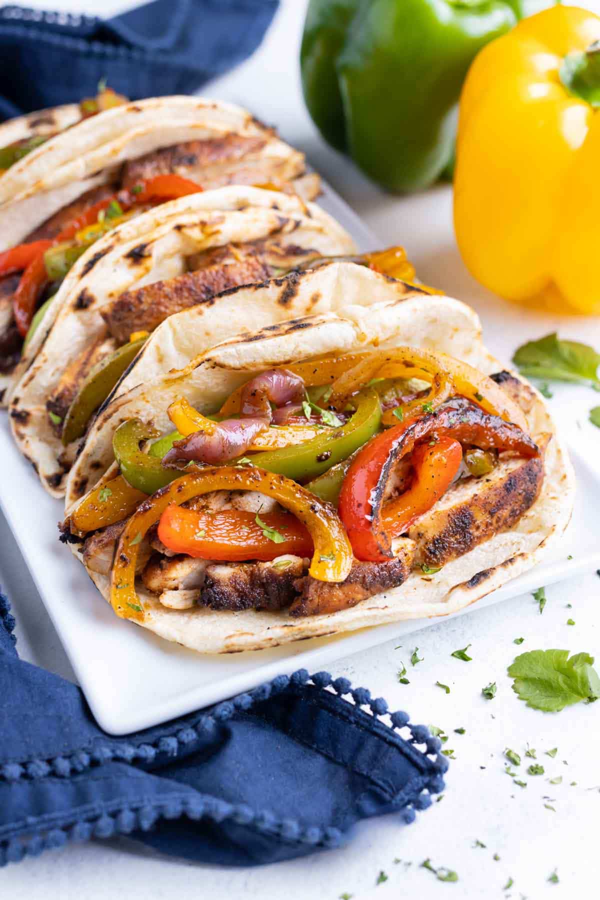 Fajita vegetables are served in tacos on a plate.