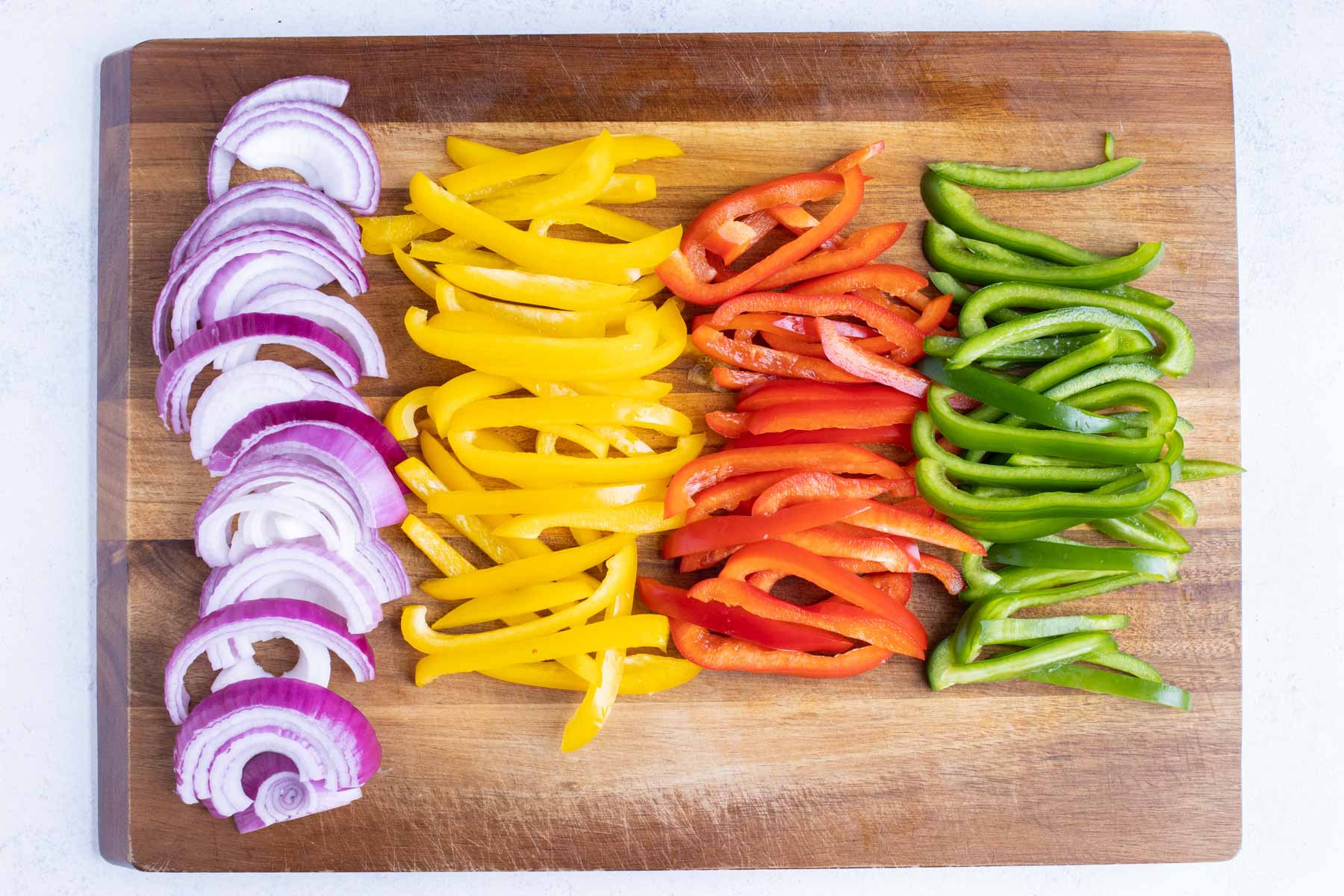 Red onions and bell peppers are cut into thin strips to make fajita veggies.