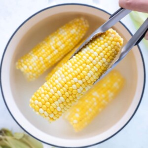 Tongs are used to remove the corn from the water.
